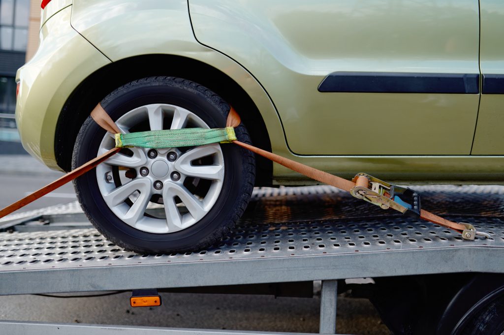 A car secured on a recovery transporter for careful towing.