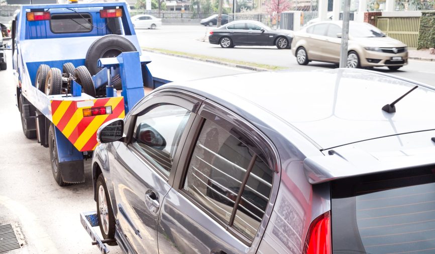 Tow truck towing a broken down car on the street Tow truck towing a broken down car on the street.